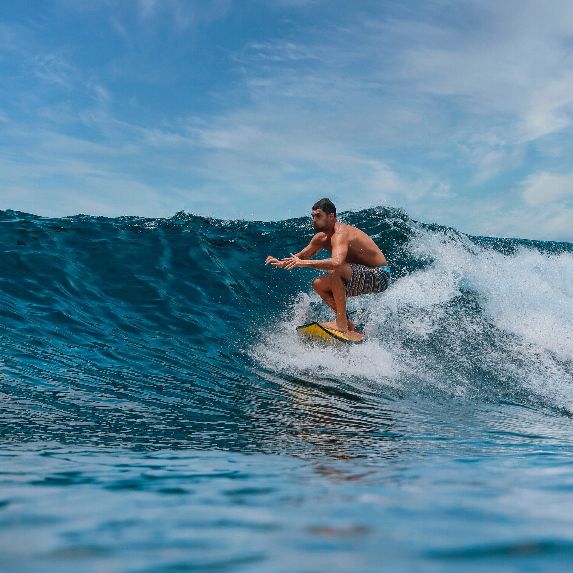 Male surfer on a blue wave at Bali island